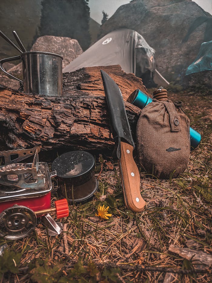 Close-up of camping tools and equipment arranged near a tent.